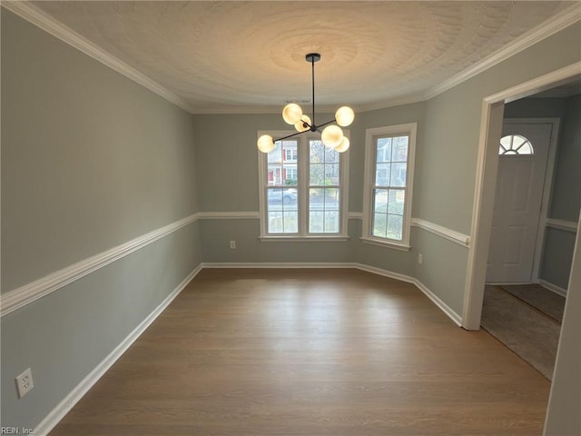 unfurnished dining area featuring crown molding, baseboards, dark wood finished floors, and a notable chandelier