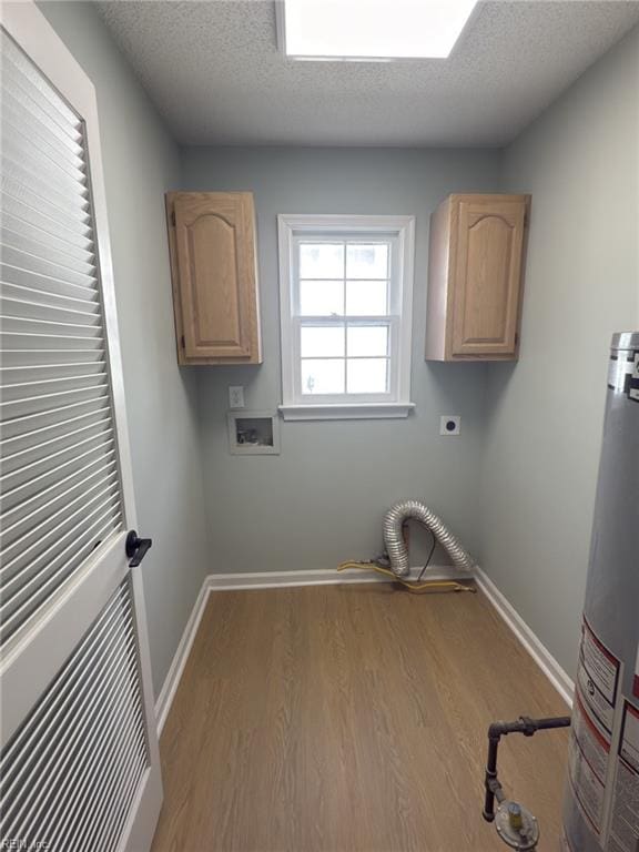 clothes washing area with baseboards, cabinet space, electric dryer hookup, and a textured ceiling