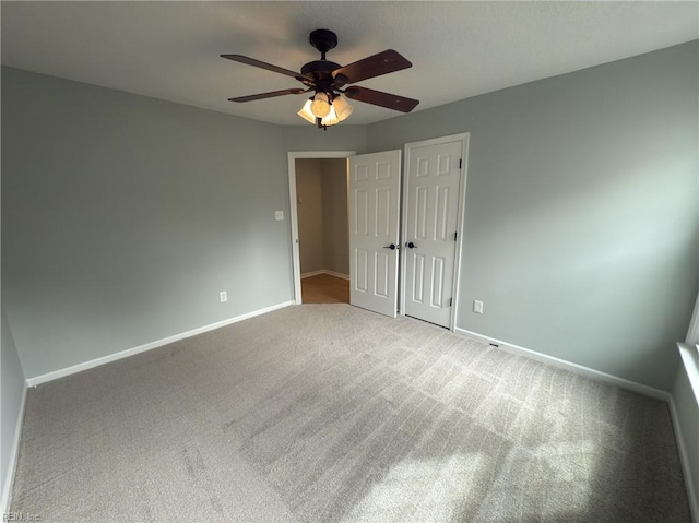 unfurnished bedroom with carpet, baseboards, ceiling fan, and a closet