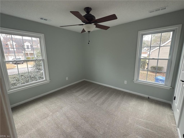 spare room featuring a textured ceiling, carpet flooring, and visible vents