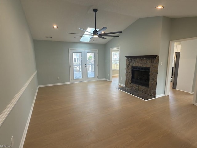 unfurnished living room with baseboards, lofted ceiling, wood finished floors, french doors, and a fireplace