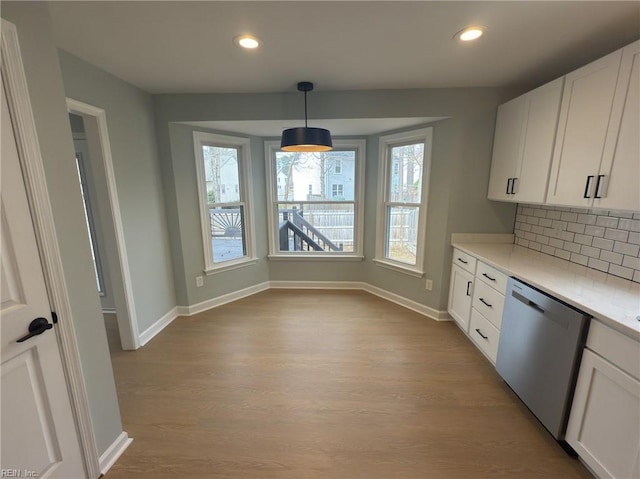 kitchen featuring wood finished floors, white cabinets, light countertops, decorative backsplash, and dishwasher