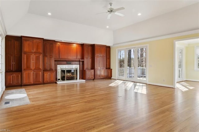 unfurnished living room featuring visible vents, baseboards, light wood-style flooring, ceiling fan, and a high end fireplace