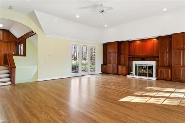 unfurnished living room with ceiling fan, recessed lighting, a premium fireplace, light wood-style floors, and stairs