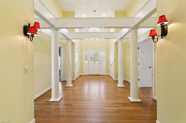 entrance foyer with baseboards, ornate columns, and wood finished floors