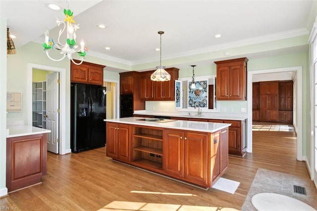 kitchen with light wood-style flooring, a sink, light countertops, a center island, and black appliances