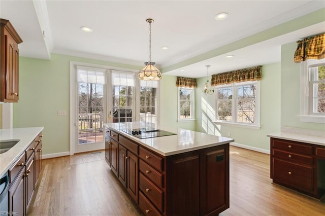 kitchen with ornamental molding, light countertops, light wood-style flooring, and black electric stovetop