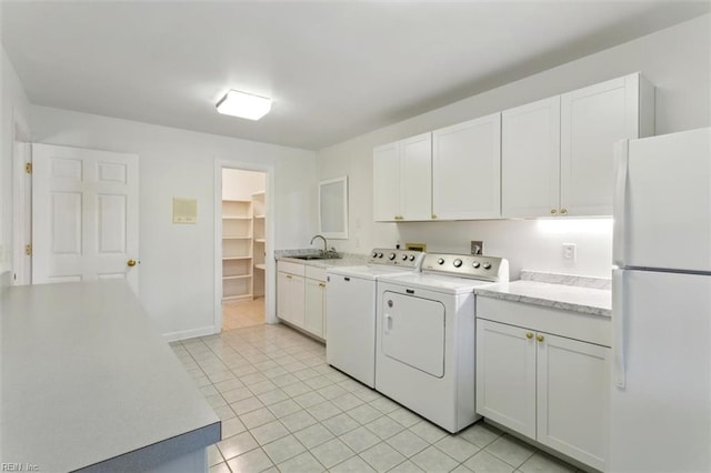 clothes washing area with washer and clothes dryer, light tile patterned flooring, a sink, and baseboards