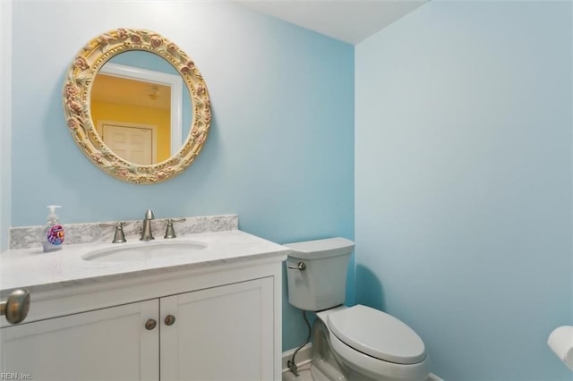 half bath with vanity, toilet, and baseboards