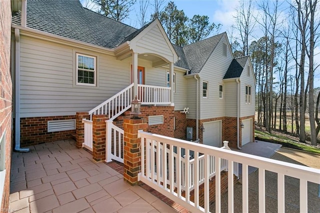 exterior space with a shingled roof, brick siding, driveway, and a garage