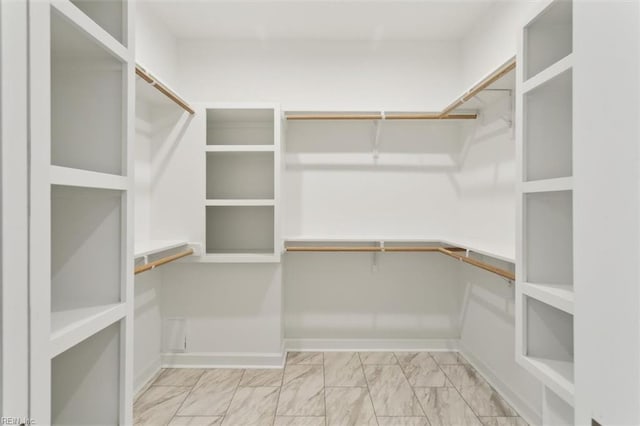 walk in closet featuring marble finish floor