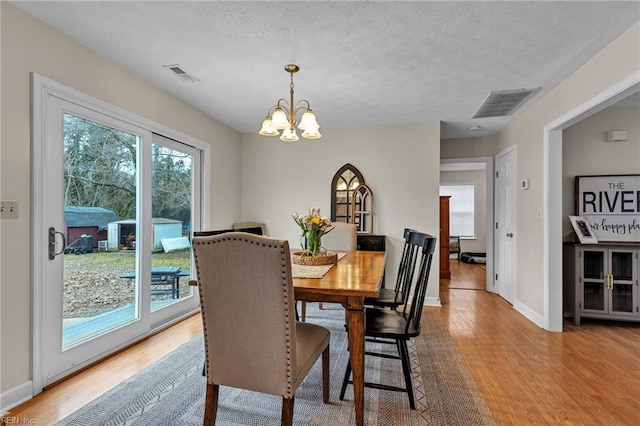 dining room with light wood-style floors, visible vents, and an inviting chandelier