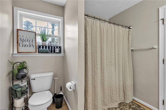 bathroom with a shower with curtain, toilet, and baseboards