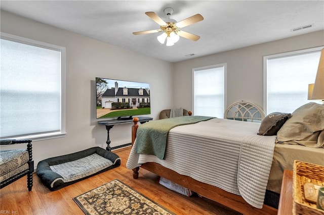 bedroom with multiple windows, wood finished floors, visible vents, and a ceiling fan