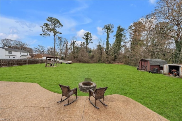 view of yard featuring an outdoor fire pit, a patio area, fence, a shed, and an outdoor structure