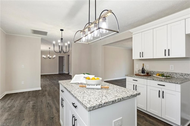 kitchen featuring light stone countertops, dark wood-style floors, a kitchen island, and visible vents