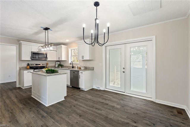 kitchen featuring a chandelier, stainless steel appliances, ornamental molding, and white cabinets