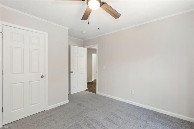 unfurnished bedroom featuring crown molding, carpet floors, ceiling fan, and baseboards