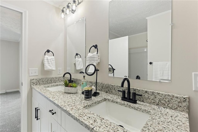 full bathroom featuring ornamental molding, a sink, a textured ceiling, and double vanity