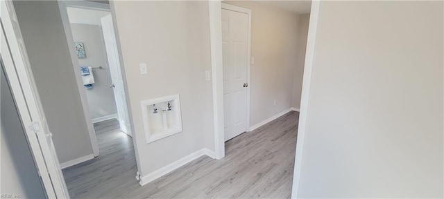 corridor featuring light wood finished floors and baseboards