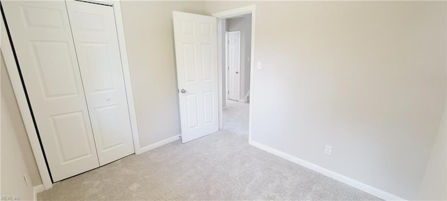 unfurnished bedroom featuring light carpet, a closet, and baseboards