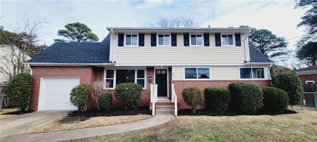 traditional-style home with concrete driveway, roof with shingles, an attached garage, fence, and brick siding