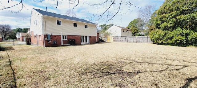 back of property with a yard, fence, and brick siding