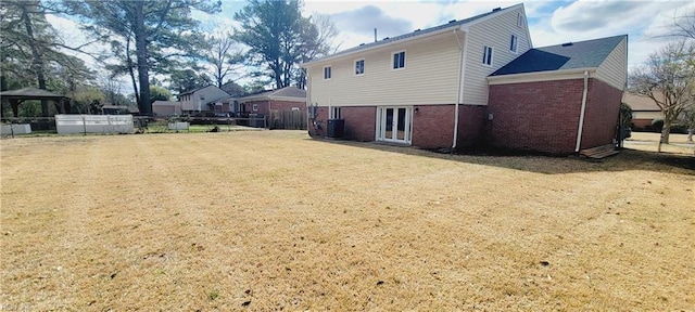 back of property with brick siding, fence, a gazebo, french doors, and a lawn