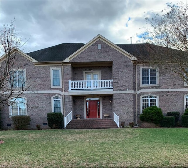 view of front of home featuring crawl space, brick siding, a balcony, and a front lawn