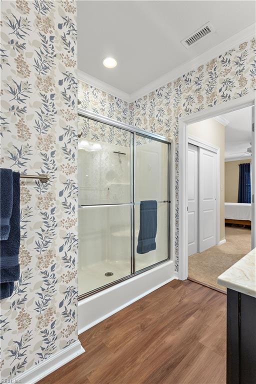 full bathroom with visible vents, a shower stall, vanity, wood finished floors, and wallpapered walls