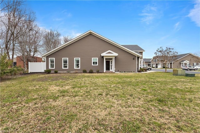 rear view of house with a lawn and fence