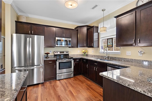 kitchen featuring stone countertops, wood finished floors, a sink, visible vents, and appliances with stainless steel finishes