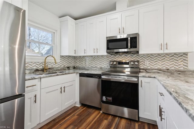 kitchen with stainless steel appliances, tasteful backsplash, dark wood-type flooring, white cabinets, and a sink