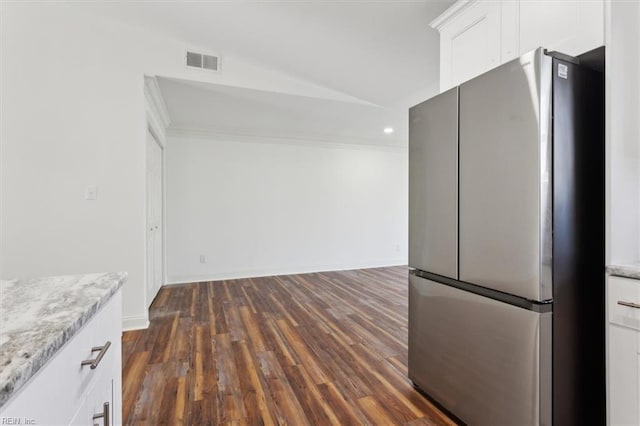 kitchen featuring dark wood-type flooring, freestanding refrigerator, visible vents, and white cabinetry