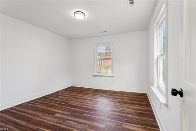 spare room featuring baseboards, visible vents, and dark wood-type flooring