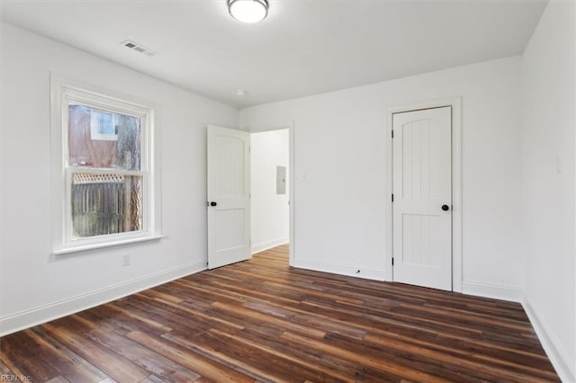 unfurnished bedroom with dark wood-type flooring, a closet, visible vents, and baseboards