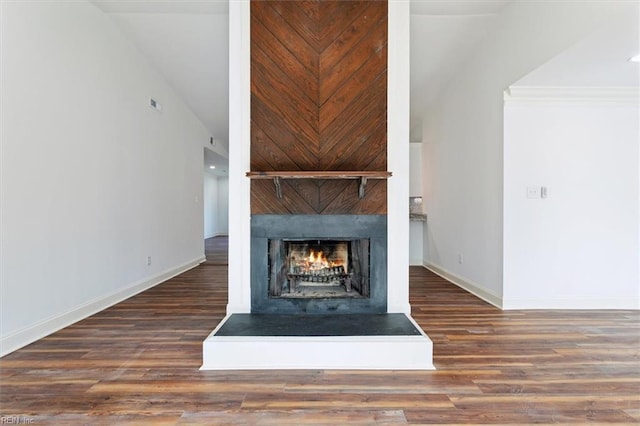 interior details featuring a large fireplace, baseboards, and wood finished floors