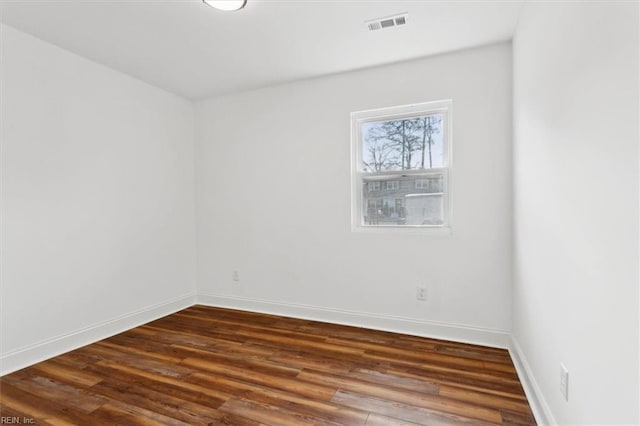 empty room with visible vents, baseboards, and wood finished floors