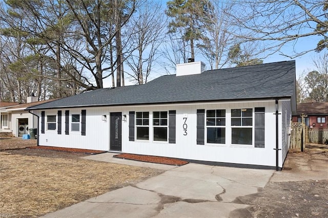 single story home with a shingled roof and a chimney