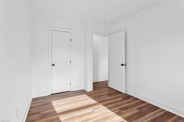 unfurnished bedroom with a closet, baseboards, and wood finished floors