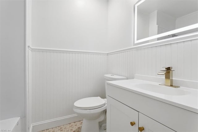 bathroom featuring a wainscoted wall, vanity, toilet, and tile patterned floors