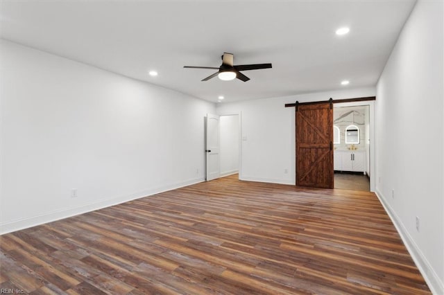 interior space with a barn door, baseboards, dark wood finished floors, a ceiling fan, and recessed lighting