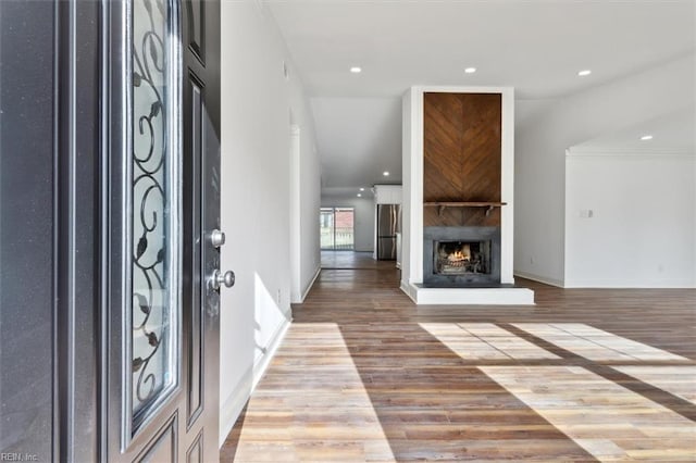 entrance foyer with a large fireplace, baseboards, wood finished floors, and recessed lighting