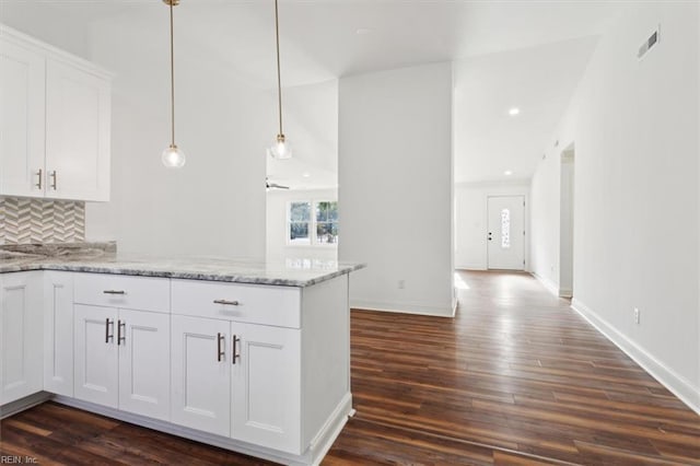 kitchen with dark wood-style flooring, visible vents, decorative backsplash, white cabinetry, and a peninsula