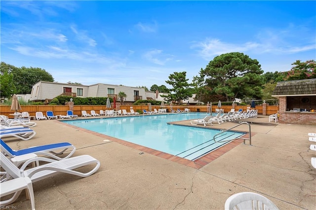 community pool with fence and a patio