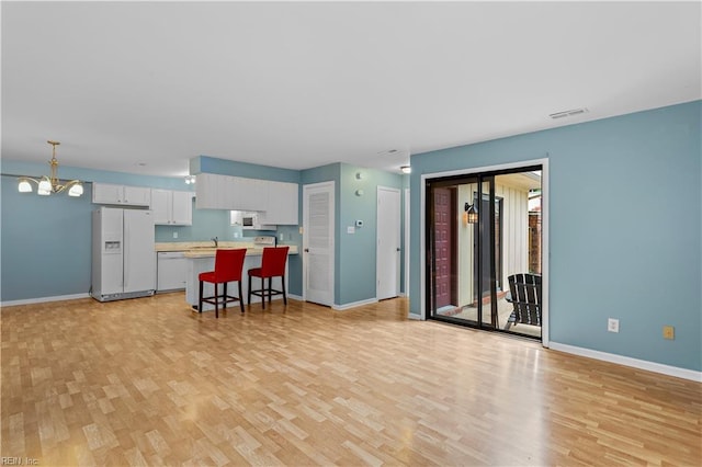 interior space with a notable chandelier, white appliances, a breakfast bar, a sink, and light countertops