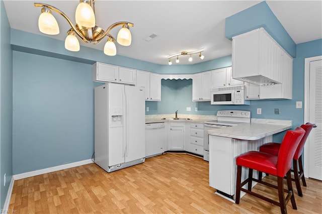 kitchen featuring white appliances, visible vents, a peninsula, light countertops, and a sink