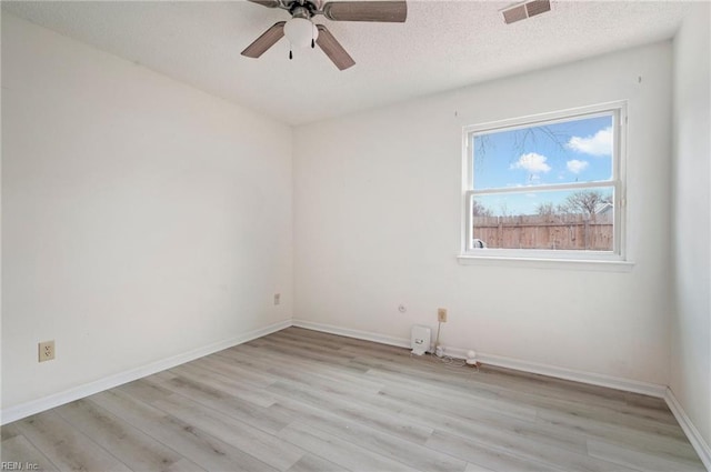 spare room with baseboards, visible vents, a ceiling fan, a textured ceiling, and light wood-type flooring