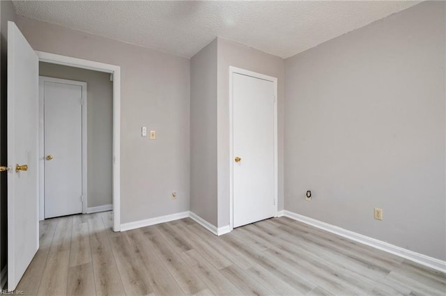 unfurnished bedroom with light wood-type flooring, baseboards, and a textured ceiling