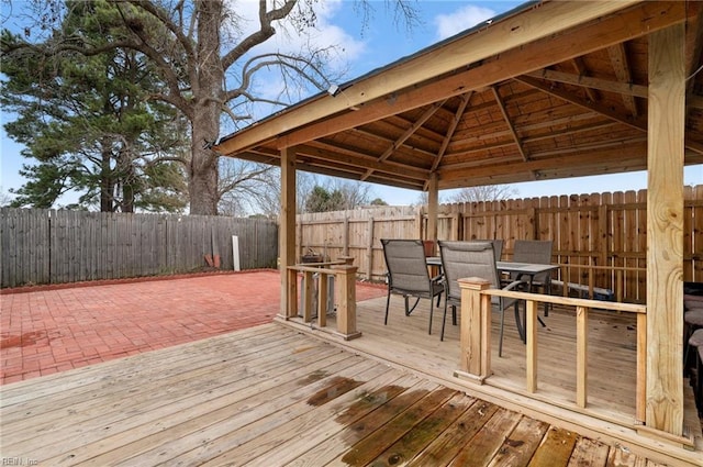 wooden deck with a fenced backyard, outdoor dining area, and a gazebo